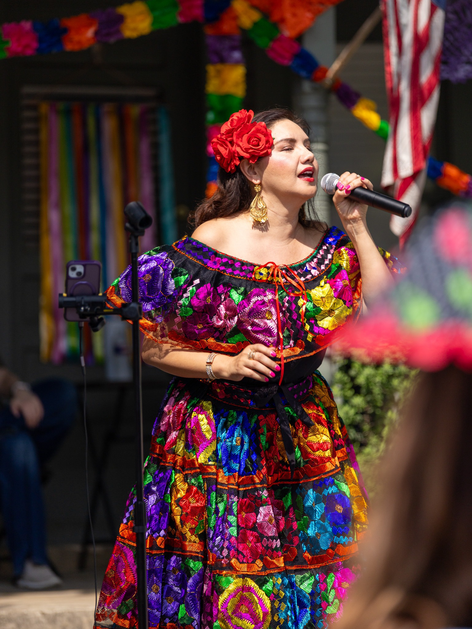Performer singing in a vibrant embroidered dress