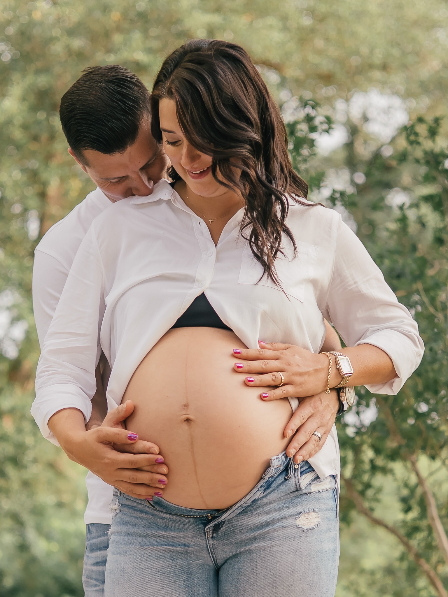 Intimate maternity portrait framed by soft natural greenery