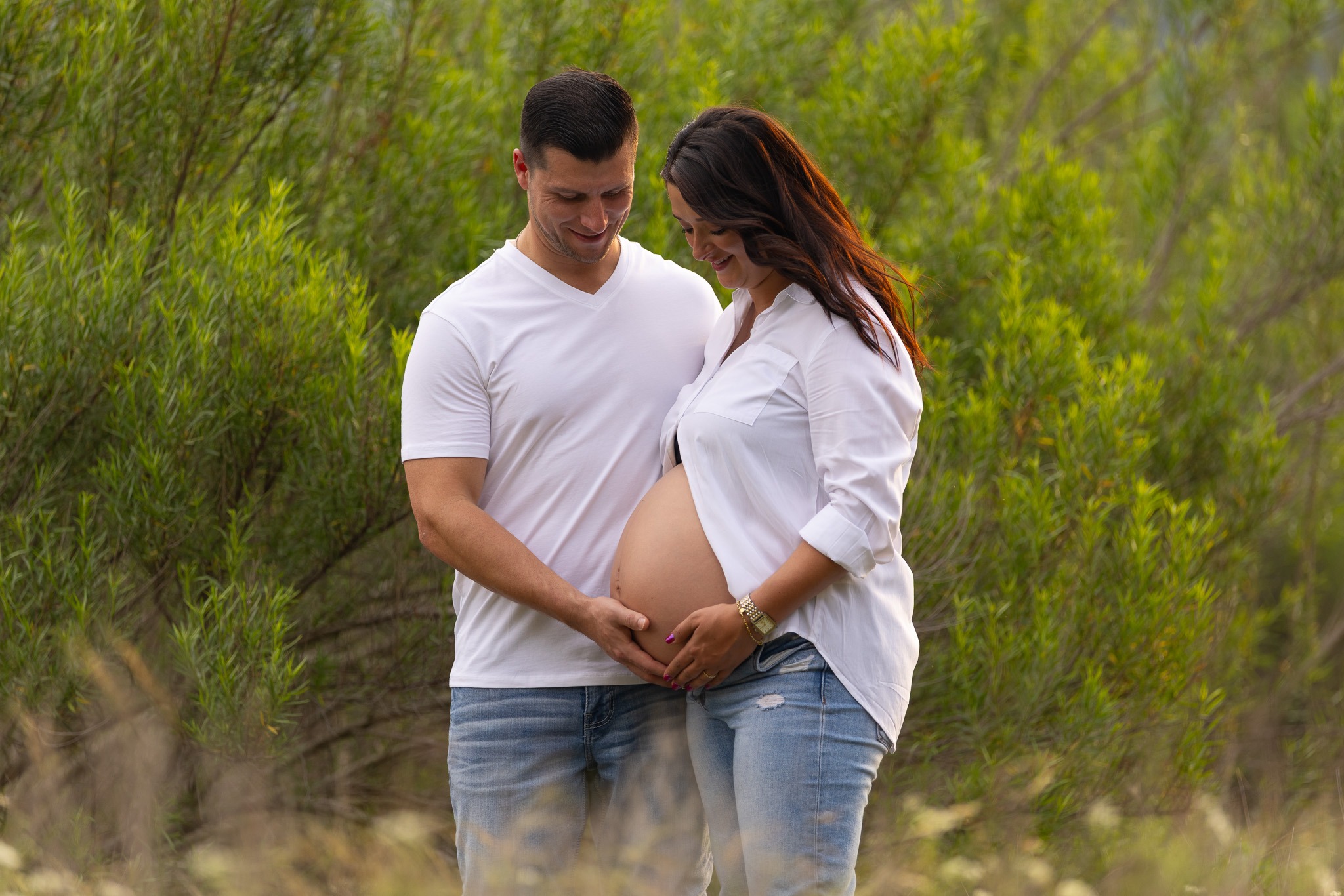 Expectant parents sharing a quiet connection in a natural field setting