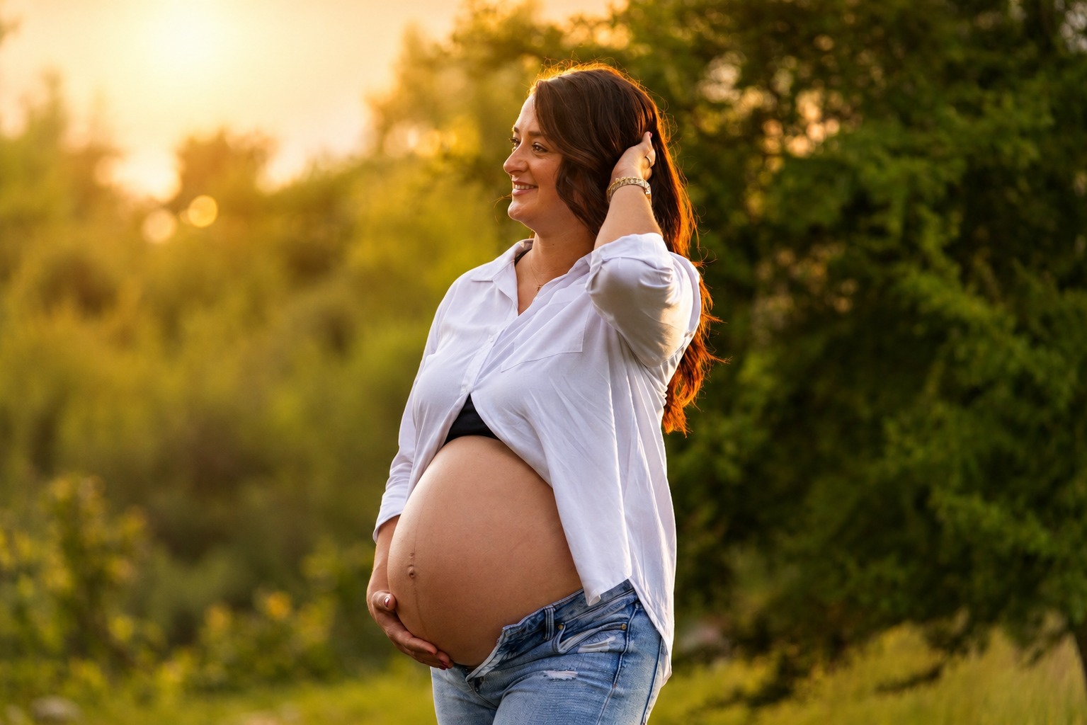Expectant mother photographed in warm golden-hour light in an open field
