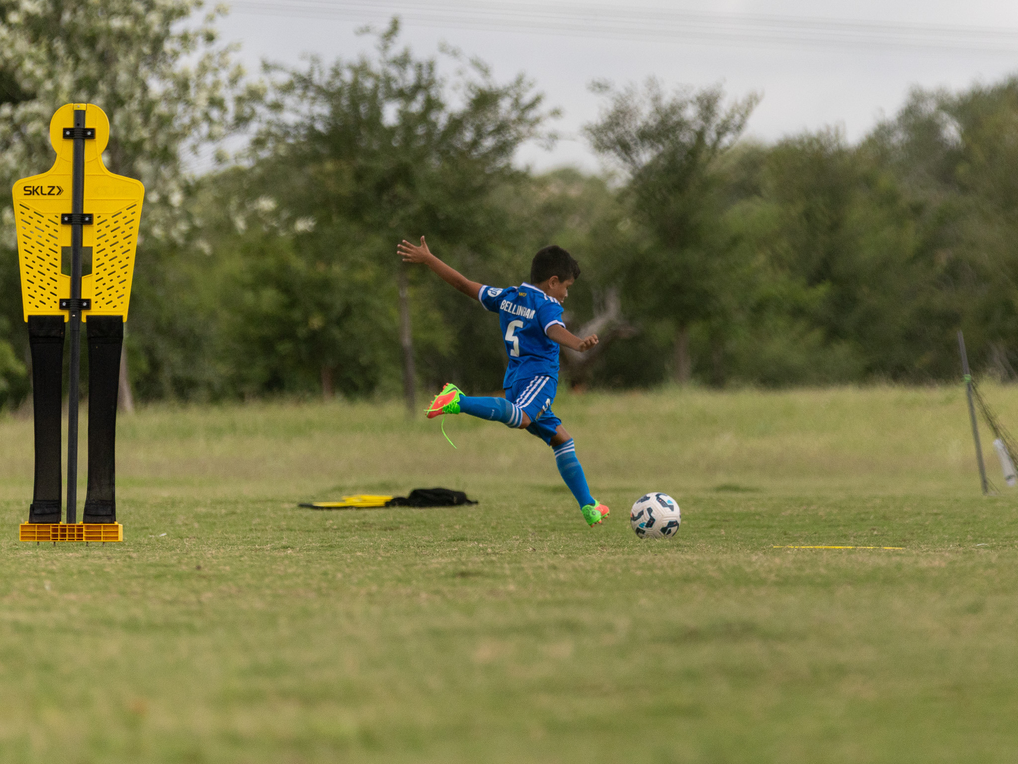 Young soccer athlete striking the ball with full extension during training