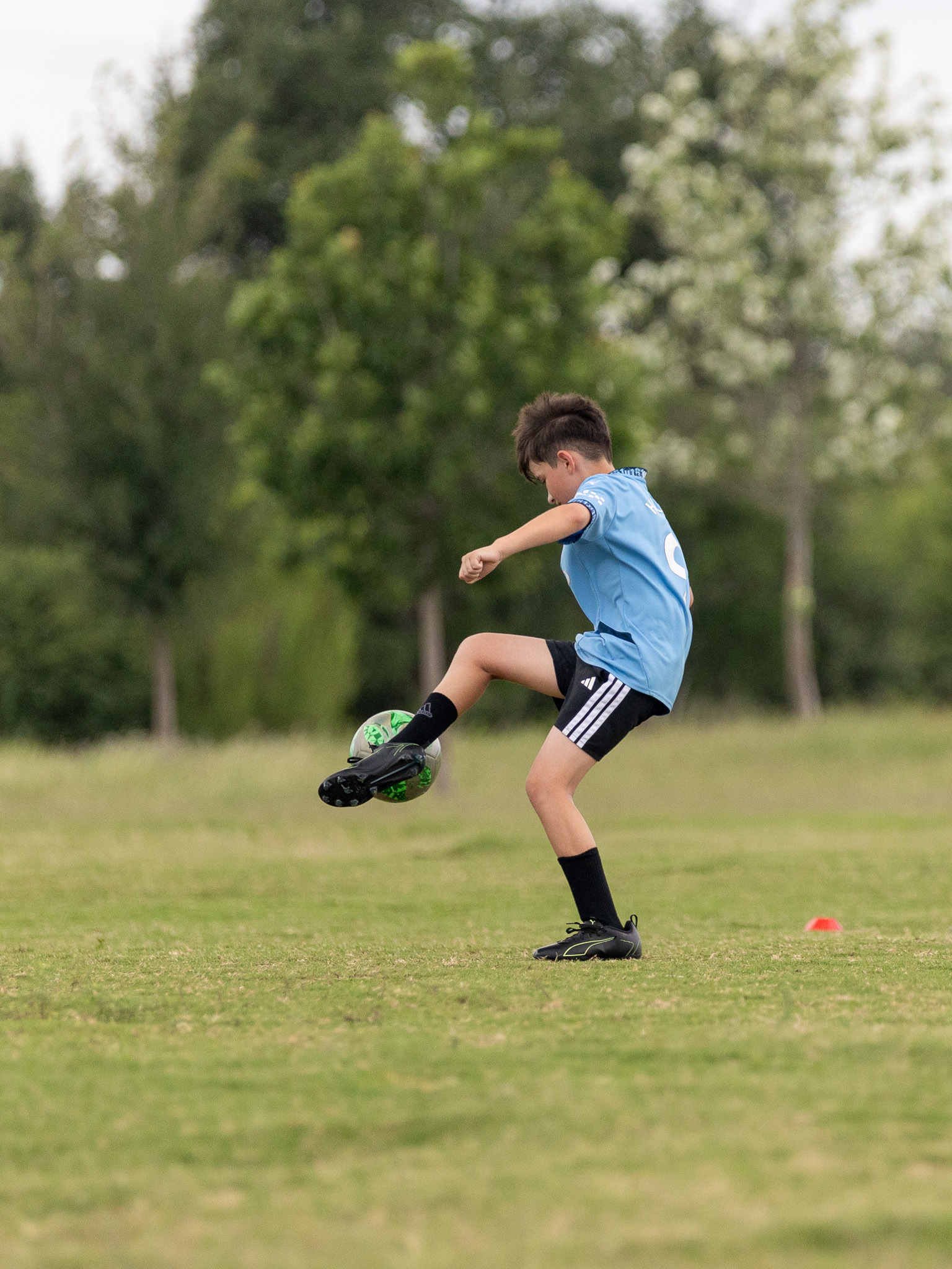 Young soccer athlete controlling the ball during an open field training drill