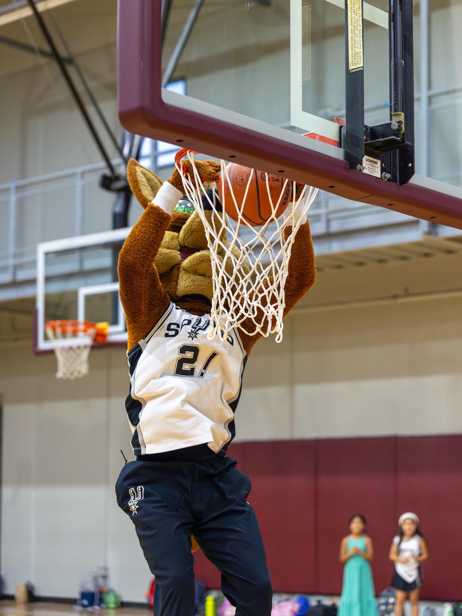 Professional basketball mascot finishing a dunk during youth camp