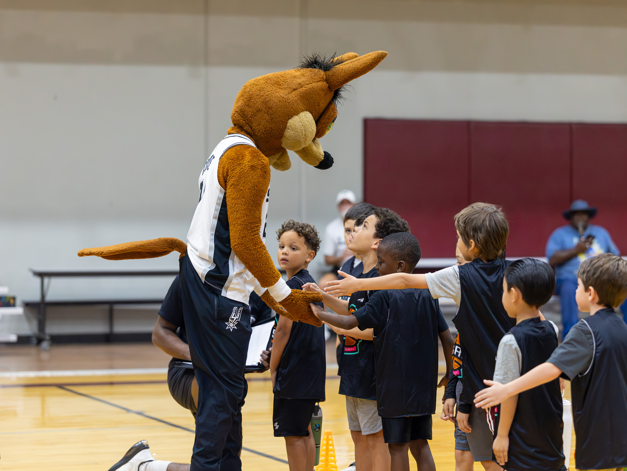 Basketball mascot engaging young athletes during camp